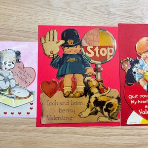 May include: Three vintage Valentine's Day cards. The cards feature illustrations of puppies, a police officer with a dog, and a child with kittens. The cards have text that reads "Won't you be my Valentine?", "Look and listen, be my Valentine", and "Quit your kitten, be my Valentine."