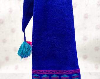 May include: A vibrant blue scarf with a decorative pattern in pink and teal near the bottom edge. The scarf has a tassel with teal and pink accents. The scarf is made of a woven material.
