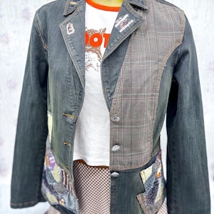 May include: A denim jacket with a patchwork design. The jacket features a mix of denim, plaid, and patterned fabrics. The collar and lapels are embellished with sequins. A white t-shirt with the word "NOT" is visible underneath.