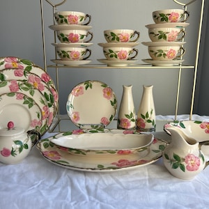Könnte beinhalten: Ein Set vintage floral Porzellan Teetassen und Untertassen, eine Kanne, eine Zuckerdose, eine Servierschüssel, eine Platte und zwei Salz- und Pfefferstreuer. Das Porzellan zeigt ein rosafarbenes Rosenmuster mit grünen Blättern.
