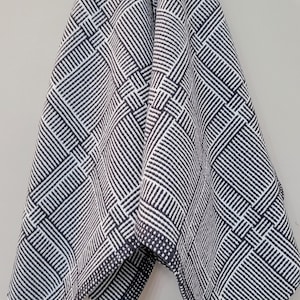 May include: A black and white geometric patterned throw blanket with a fringed edge.