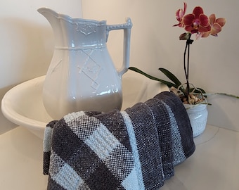 May include: A white ceramic pitcher with a decorative design sits in a white ceramic bowl. A pink orchid with a white and pink flower sits in a brown pot on a white surface.