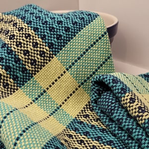 Puede incluir: Una toalla de cocina doblada con un patrón de cuadros azul, verde y amarillo.