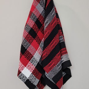 Peut inclure: Deux torchons de cuisine tissés accrochés à un crochet. L'un est à carreaux rouge, noir et blanc. L'autre est à rayures noires et rouges.