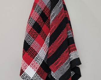 May include: Two woven kitchen towels hanging on a hook. One towel is red, black, and white plaid. The other towel is black and red stripes.