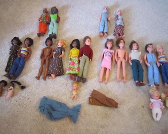 Può includere: Una collezione di bambole vintage di varie dimensioni e stili, tra cui bambole con abiti, pantaloni e camicie. Alcune bambole hanno capelli radicati, altre hanno tratti dipinti. Sono presenti anche vestiti per bambole.