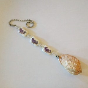 May include: A white beaded chain with purple seahorse charms and a large seashell pendant.