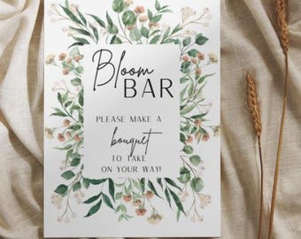 以下が含まれることがあります： 緑とピンクの花のイラストが縁取りされた白い看板。看板には「Bloom Bar」と「お帰りの際にブーケをお持ち帰りください！」と書かれています。