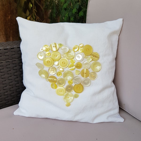 Petit coussin en coton avec un cœur en boutons jaunes