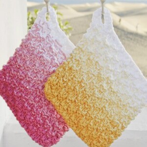 Può includere: Due strofinacci all'uncinetto appesi a ganci. Uno è rosa e bianco sfumato, l'altro è giallo e bianco sfumato.