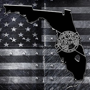 May include: Black and white metal license plate featuring the state of Florida outline with the state seal inside. The background is a distressed American flag design.