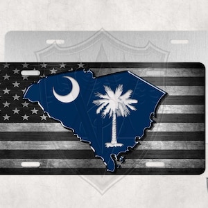 May include: A black and white American flag with a blue outline of the state of South Carolina and a white palmetto tree and crescent moon in the center.
