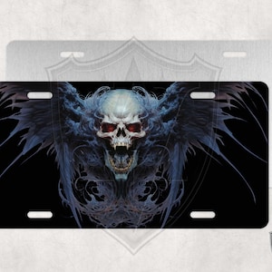 May include: A black and white license plate with a skull with red eyes and wings. The skull is surrounded by a dark blue and black design.