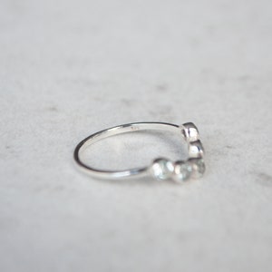May include: A silver ring with a row of small, round stones set in a curved design.