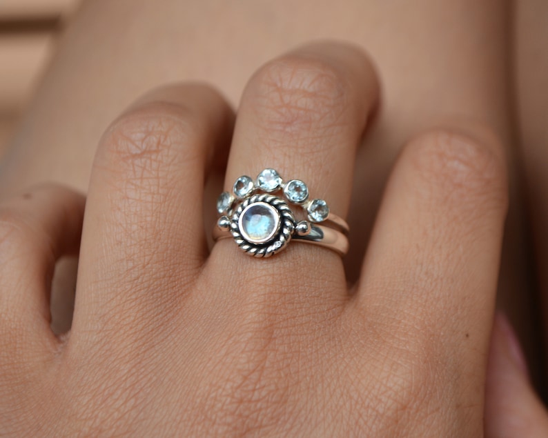 May include: A silver ring set with a large round moonstone and a smaller band of five round clear stones.