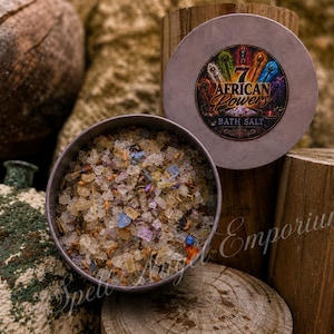 Puede incluir: Una lata metálica redonda llena de cristales de sal de baño gruesos en tonos beige, azul y morado, mezclados con trozos de plantas secas. La tapa presenta una etiqueta circular con el texto 7 African Powers Bath Salt e imágenes coloridas.