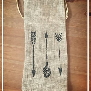 May include: A brown burlap bag with a drawstring closure. The bag has three black arrow designs printed on the front.