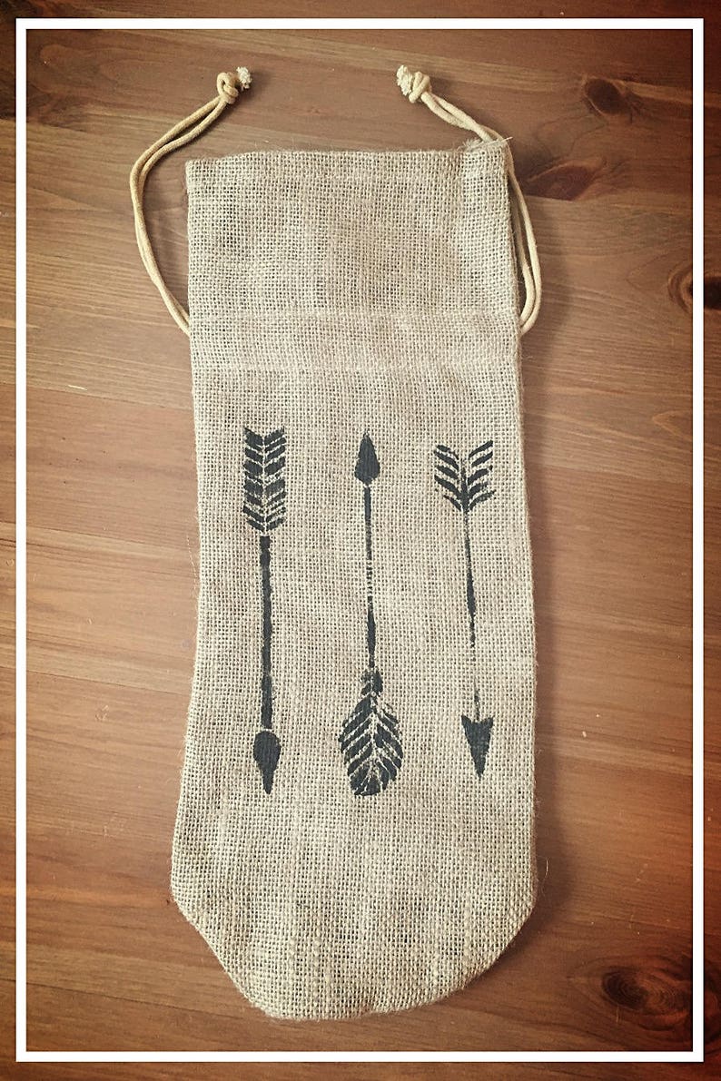 May include: A brown burlap bag with a drawstring closure. The bag has three black arrow designs printed on the front.