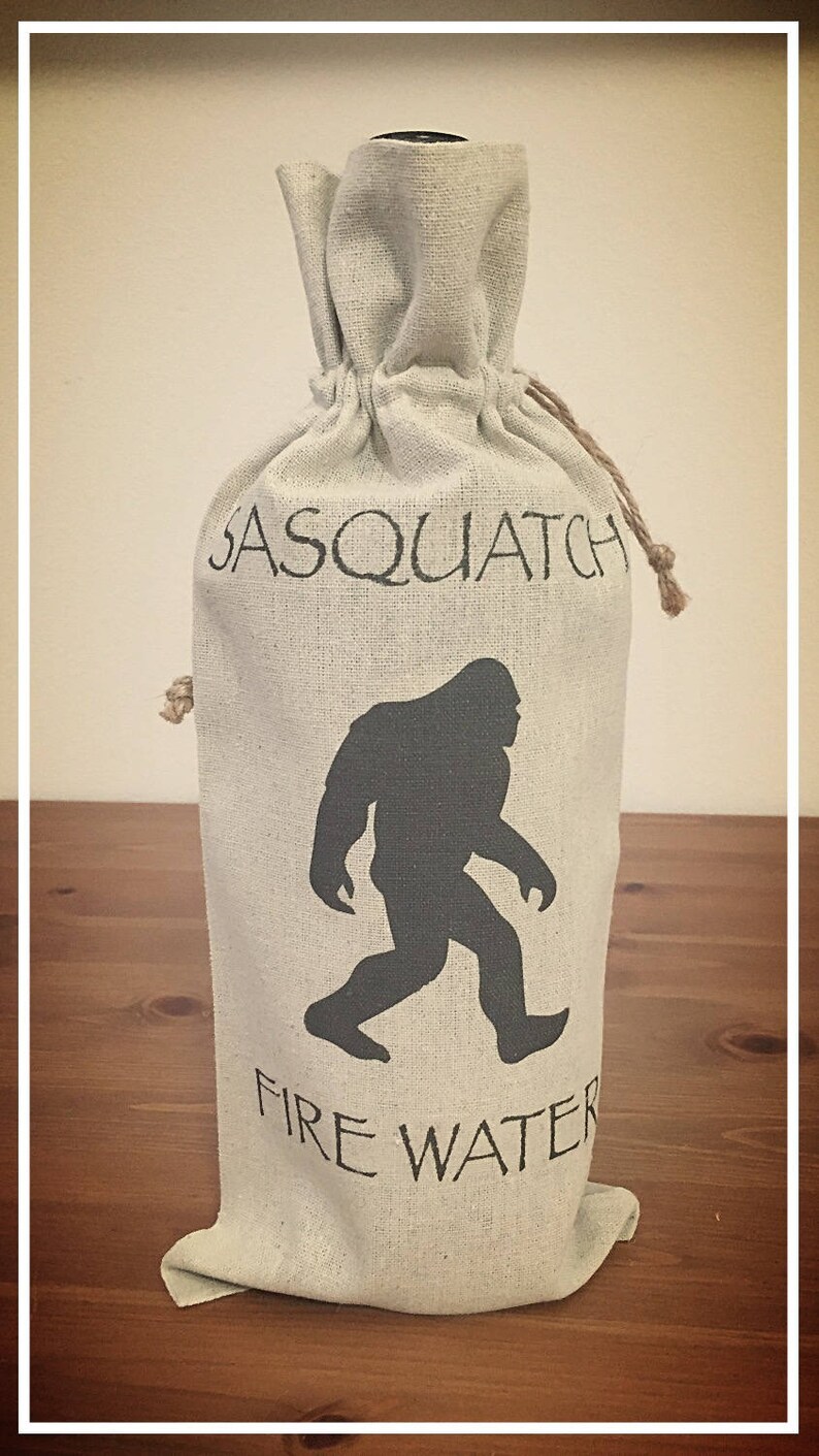 May include: A white canvas bag with a black silhouette of Bigfoot and the text "Sasquatch Fire Water".