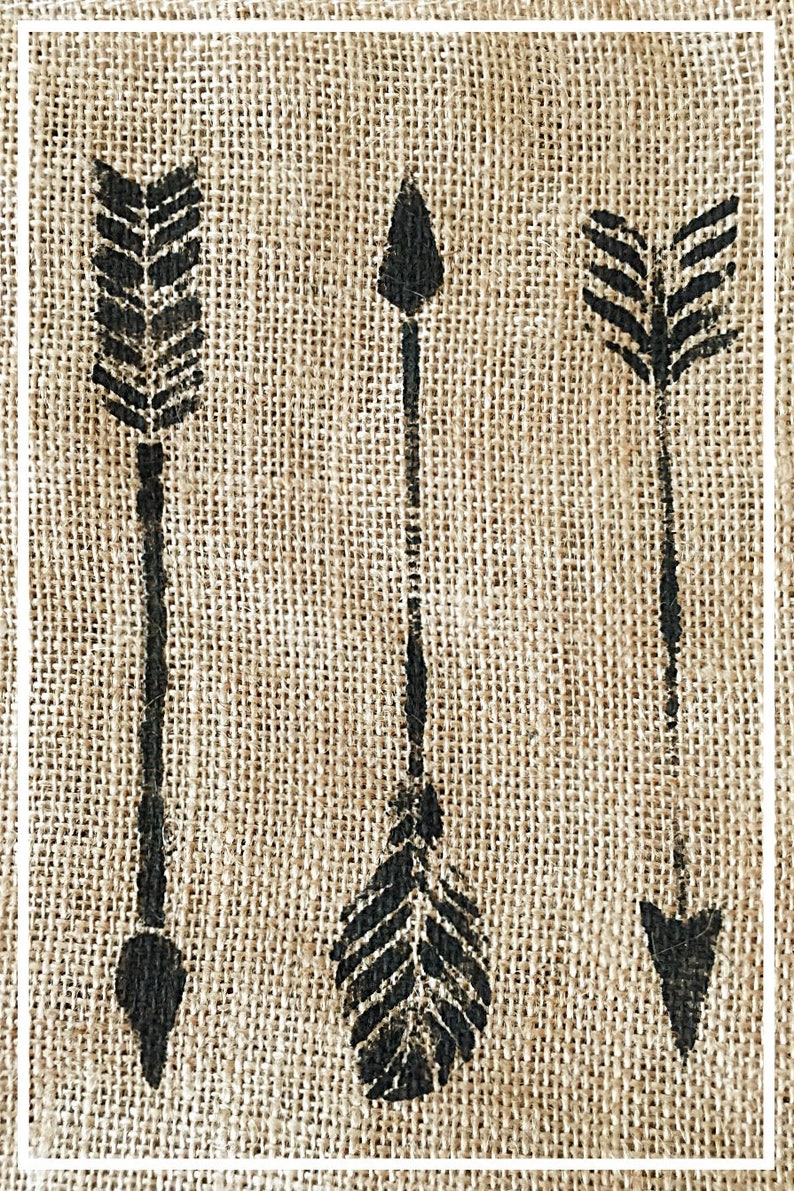 May include: Three black arrows are stenciled onto a burlap background. The arrows are different styles, with one having a feather design.