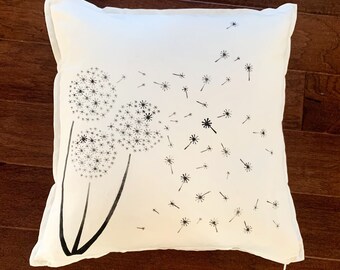 May include: White pillow with a black and white design of three dandelions with seeds blowing in the wind.