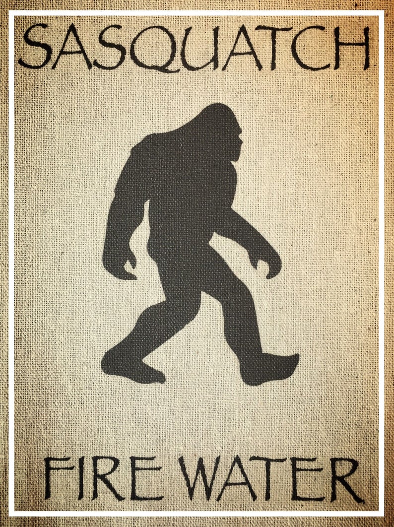 May include: A brown burlap background with the text "Sasquatch Fire Water" in black lettering. A black silhouette of a Sasquatch walking to the right is in the center of the image.