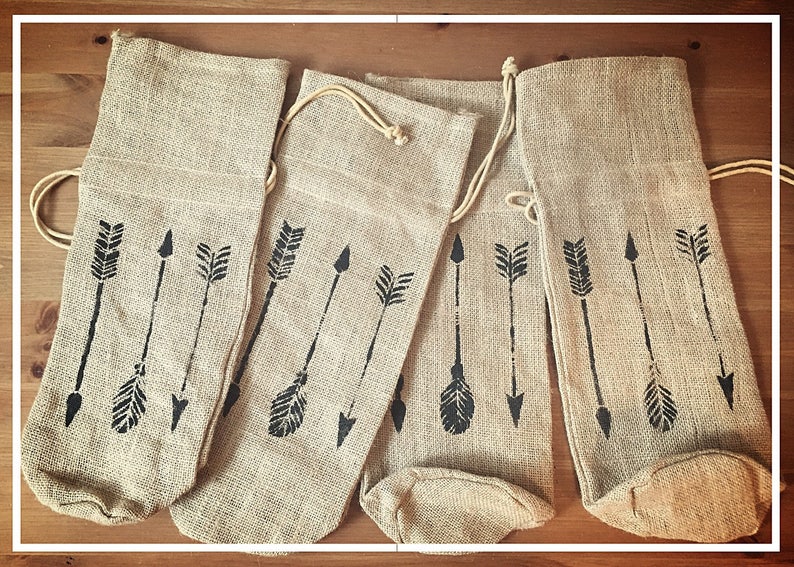 May include: Four brown burlap wine bottle bags with black arrow designs.