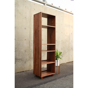 May include: A tall, wooden bookshelf with five shelves. The bookshelf is made of dark brown wood and has a simple, modern design.