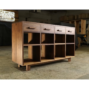 May include: A wooden cabinet with three drawers and nine open shelves. The cabinet is made of dark wood with a natural finish. The drawers have simple, rectangular pulls.