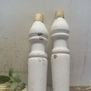 May include: Two white wooden finials with a distressed finish. The finials have a rounded top and a fluted design.