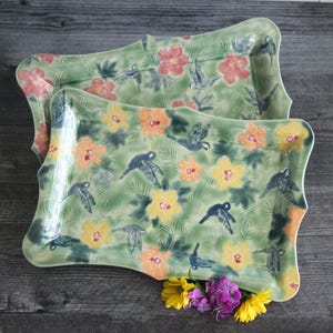 Puede incluir: Dos bandejas de servir de cerámica verde con un patrón floral de colibríes amarillos, naranja, rosa y azules y flores de hibisco.
