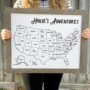 May include: A framed map of the United States with the title "Hailie's Adventures". Each state is outlined in black and labeled with its name.