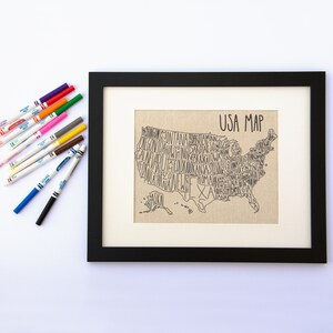 May include: A black framed print of a USA map with the states spelled out in a stylized font. The print is on a beige canvas background and has the words "USA Map" at the top.