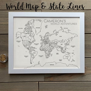May include: A white framed world map with black lines outlining countries and states. The map is titled "Cameron's World Adventures".