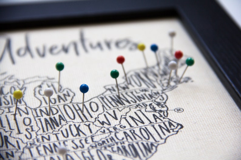 May include: A map of the United States with the word "Adventures" written at the top.  The map is decorated with colorful push pins in various states.