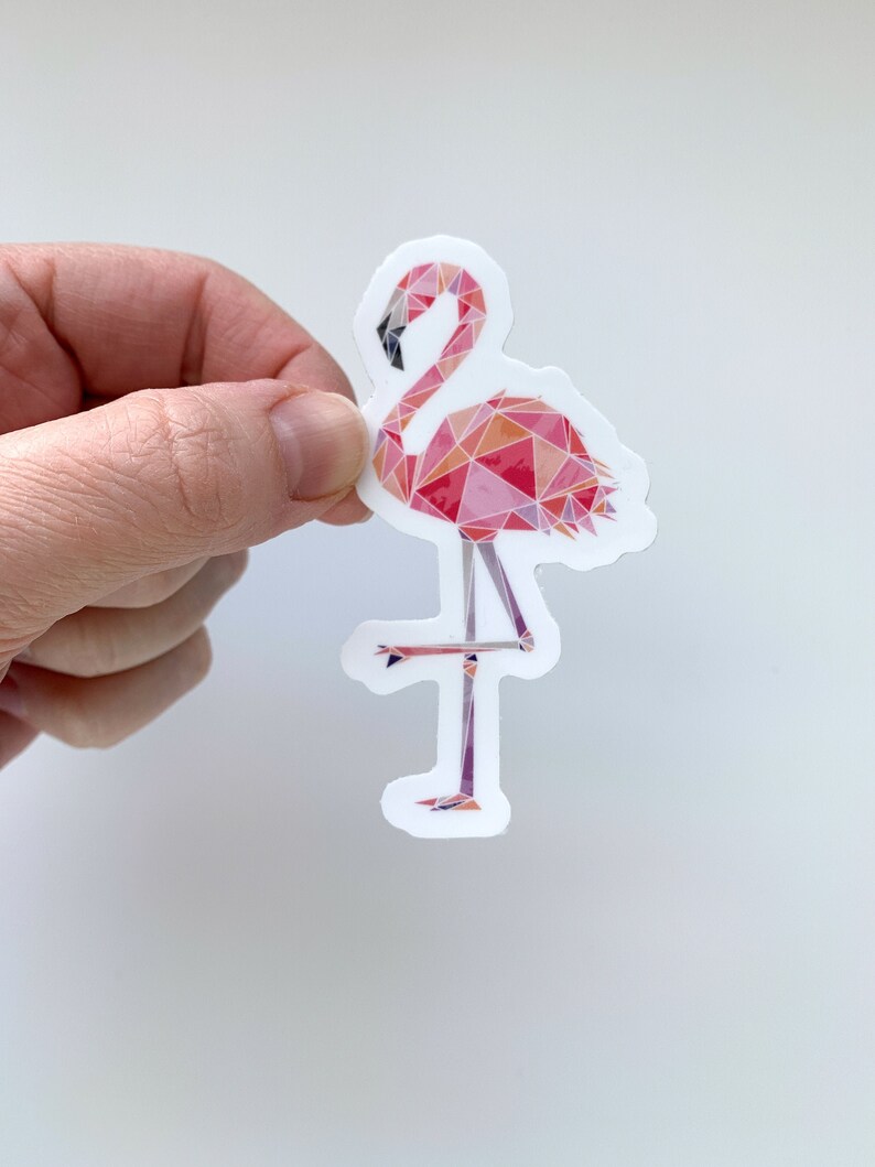 Puede incluir: Una pegatina de flamenco rosa con un dise&ntilde;o geom&eacute;trico. El flamenco est&aacute; de pie sobre una pierna con la cabeza inclinada hacia abajo.