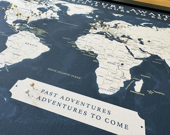 May include: A world map with gold push pins marking locations. The map is on a dark blue background with the text "Adventure Awaits" and "Past Adventures to Come" printed on the bottom.