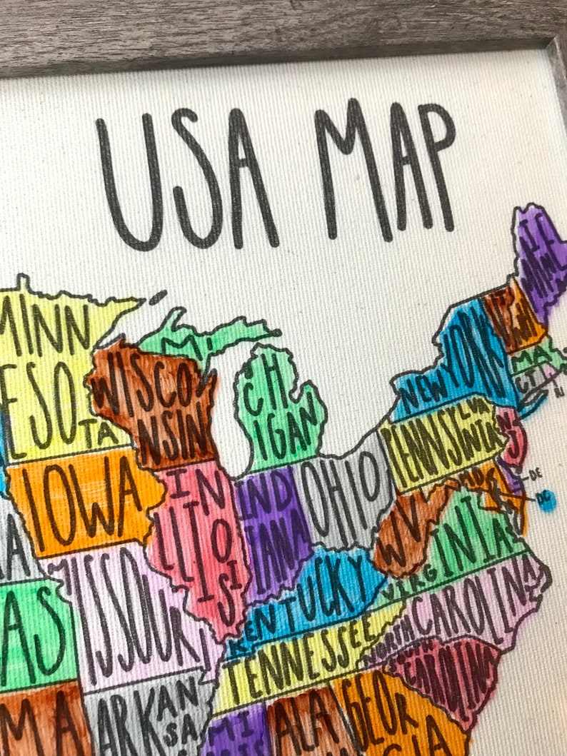 May include: A hand-drawn map of the United States with each state labeled in colorful lettering. The map is framed in a gray wood frame. The title "USA MAP" is written in black at the top of the map.