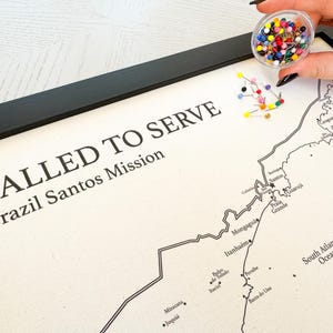 Op de afbeelding: Een ingelijste kaart van de Braziliaanse Santos-missie met de tekst "Called to Serve" en de naam van de missie. De kaart is gemarkeerd met gekleurde duimspijkers.