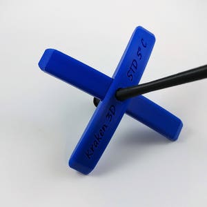 Puede incluir: Soporte de antena de plástico azul con el texto "Kraken 3D" y "STD 5/C" impreso en él. El soporte está diseñado para sostener una antena negra.