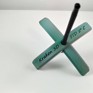 Puede incluir: Una rueca verde y blanca con un huso negro. La rueca está etiquetada con "Kraken 3D" y "STD 5" C".