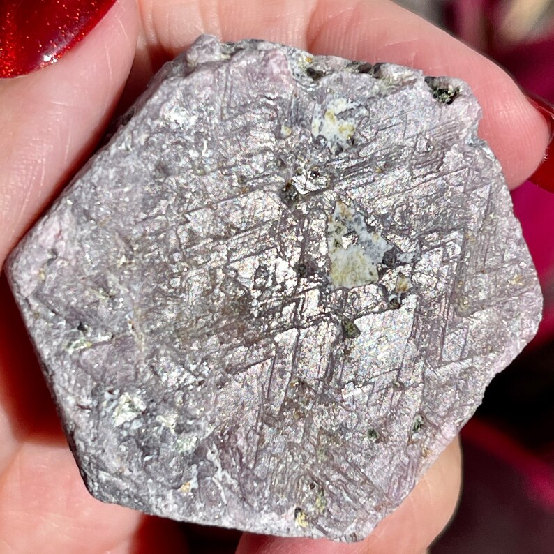 K&ouml;nnte beinhalten: Ein gro&szlig;er, rauer, sechseckiger, purpurgrauer Rubin-Kristall mit silbernem Schimmer. Der Kristall hat ein nat&uuml;rliches, unpoliertes, rohes Aussehen.