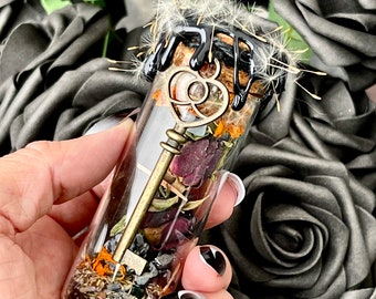 May include: A glass vial filled with dried flowers, herbs, and a gold key. The vial is sealed with a black wax and topped with a dandelion seed head.