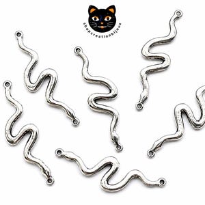 Peut inclure: Cinq breloques serpent en métal argenté disposées en motif dispersé. Chaque breloque présente un long corps sinueux avec une petite boucle circulaire aux extrémités de la tête et de la queue pour la fixation. La surface a une finition antique texturée.