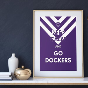 May include: A framed print with a purple background and white stripes. The print says "Keep Calm and Go Dockers" with an anchor symbol at the top.
