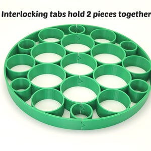 May include: A bright green, circular object with multiple cylindrical openings. The text "Interlocking tabs hold 2 pieces together" is printed at the top. The design features interlocking tabs to hold two pieces together.