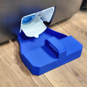Può includere: Un vassoio raccogligocce in plastica blu per un distributore d'acqua da frigorifero. Il vassoio presenta una base rettangolare con una maniglia centrale e il testo in rilievo "Yalni Creations" sul bordo anteriore, sotto l'erogatore bianco.