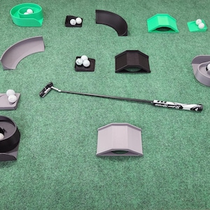 May include: A golf putter with a black shaft and white grip positioned among various plastic putting practice obstacles, including green, black, and grey ramps, tunnels, and spiral ball traps, all scattered with white golf balls.