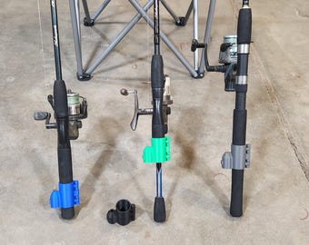 May include: Three black fishing rods with spinning reels, each equipped with a different colored plastic rod holder attachment in blue, green, and gray. A separate black plastic rod holder attachment sits on the ground between the rods.
