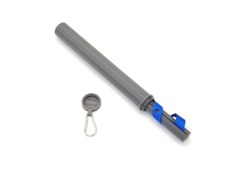 May include: A gray cylindrical storage tube with a threaded cap and a blue strap attached to the base. Beside the tube is a small circular gray cap featuring the text Yalotz Creations and a silver metal carabiner clip attached to it.